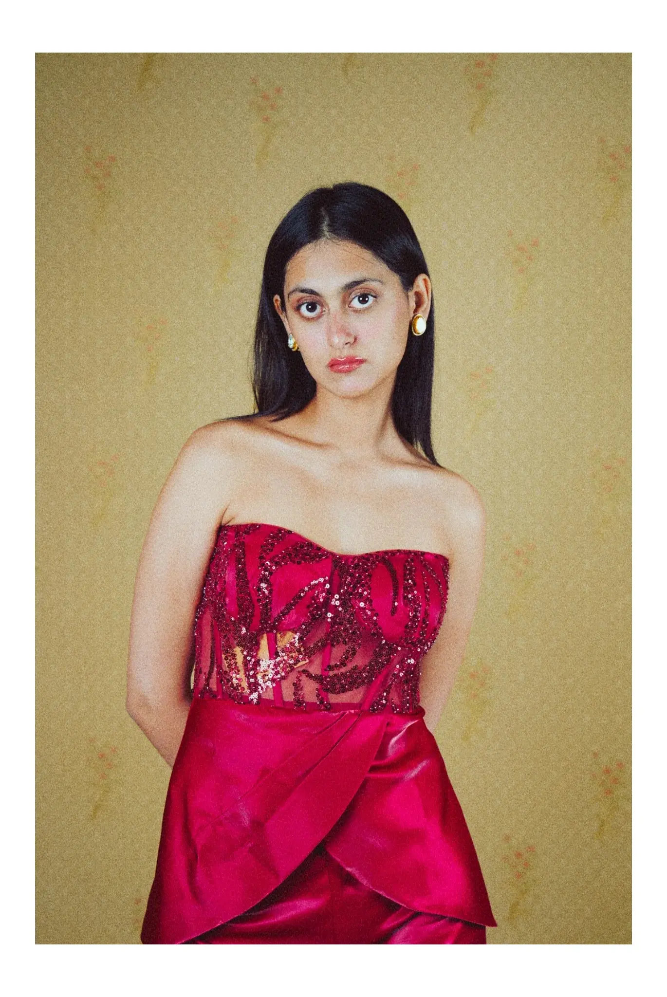 Model in a red satin dress against an olive wall