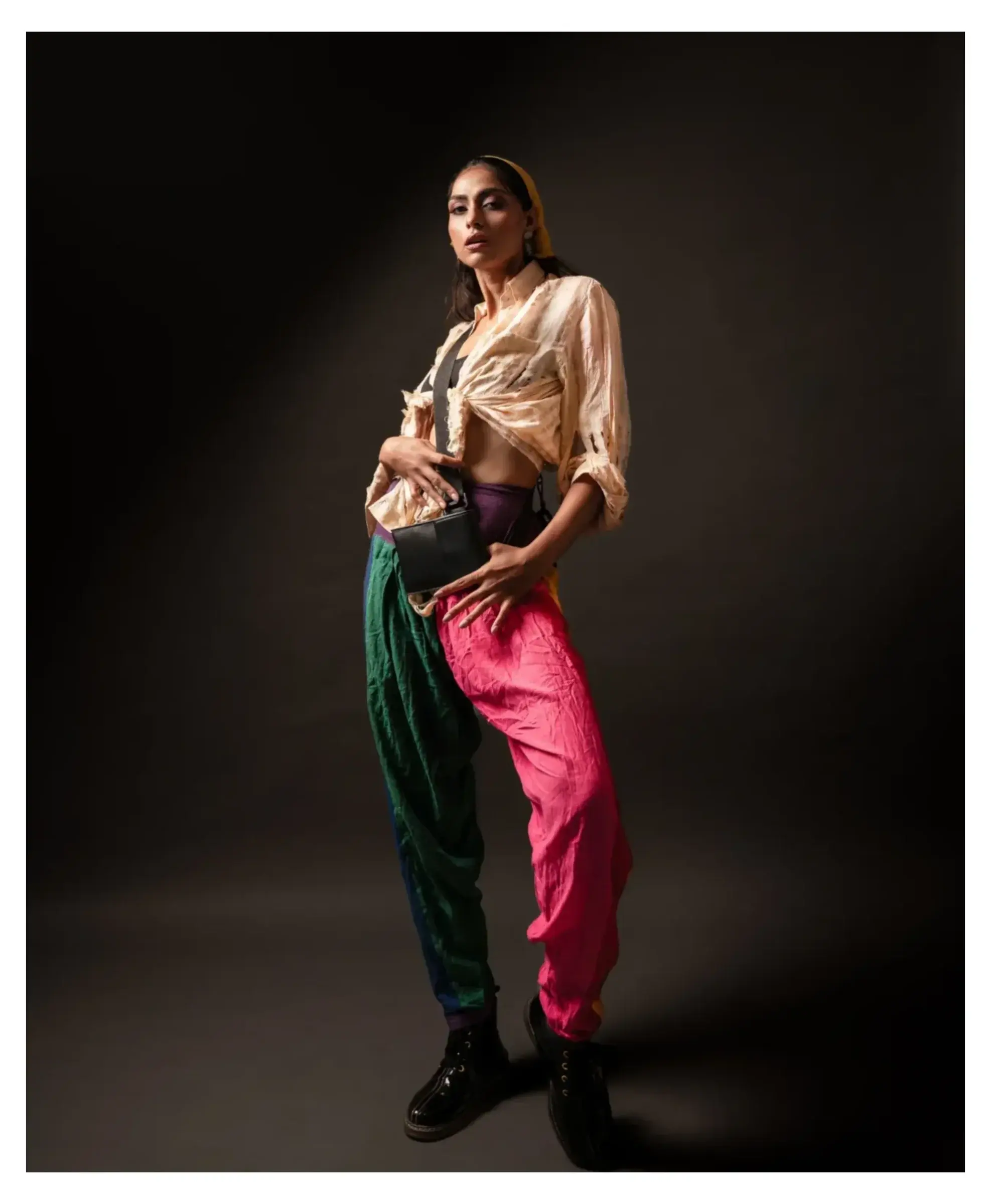 Full-length fashion portrait in a beige blouse and green and pink draped trousers
