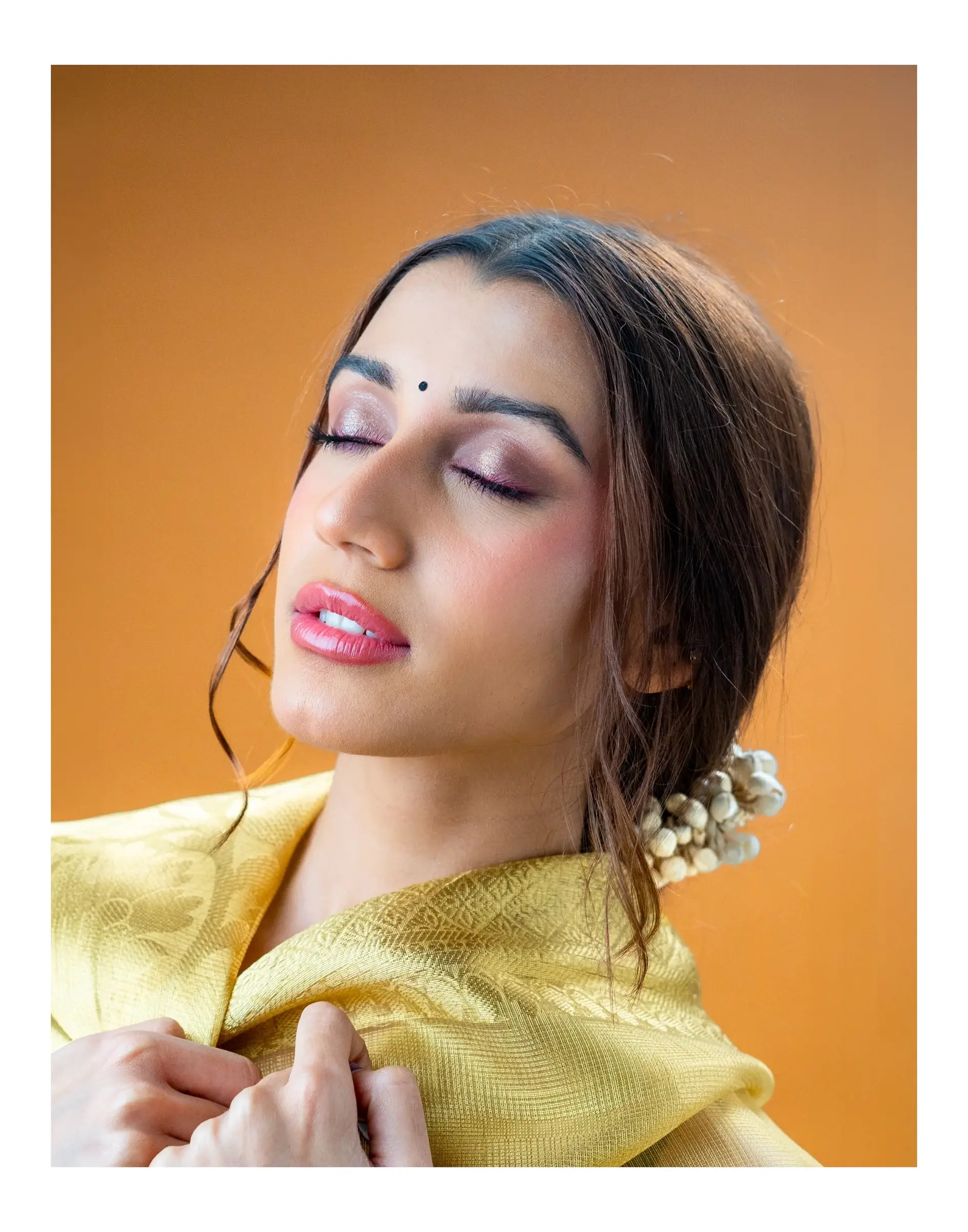 Close portrait framed by pale green fabric and silver earrings