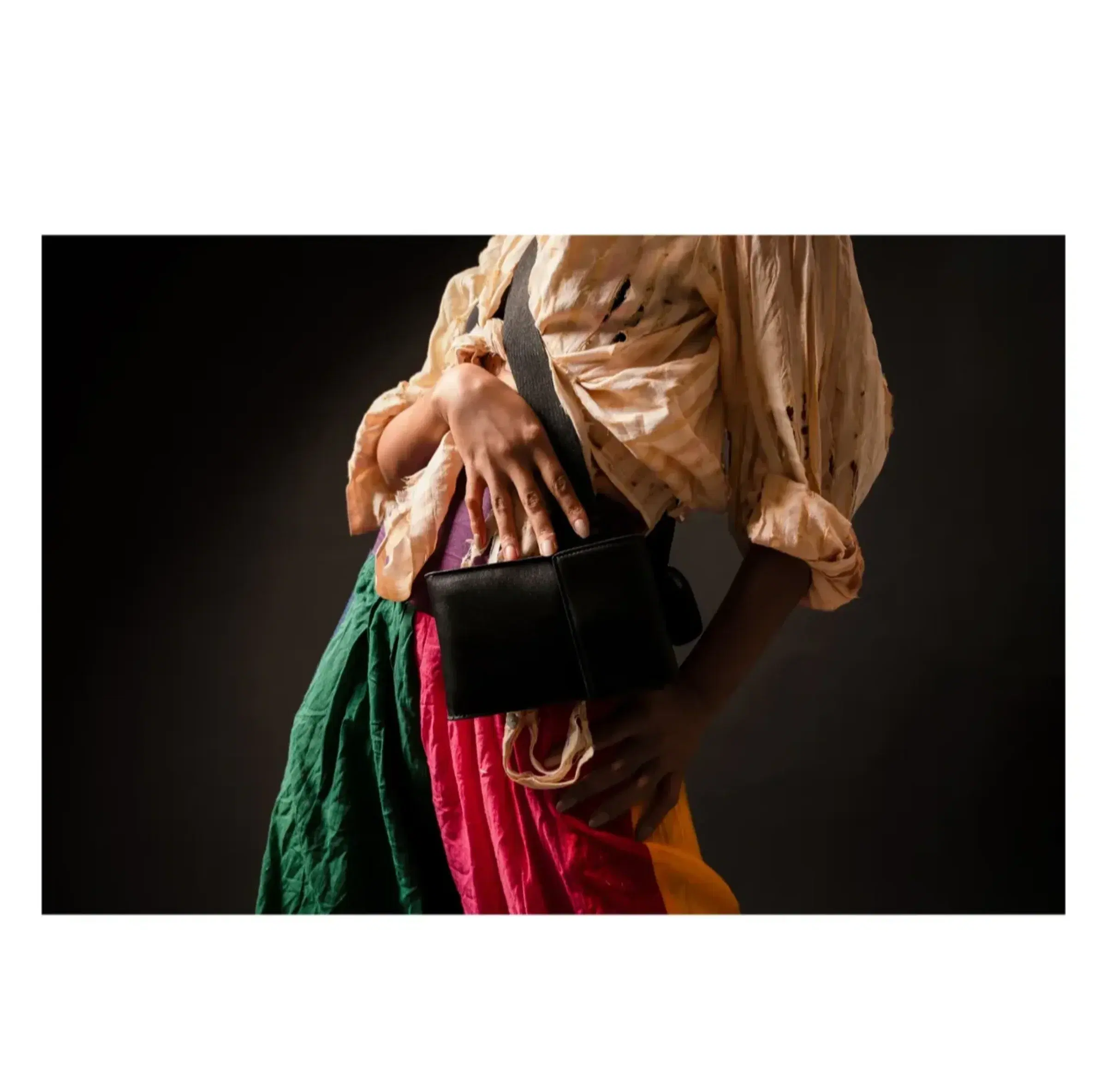 Detail of silk fabric, a black handbag and a model’s hands