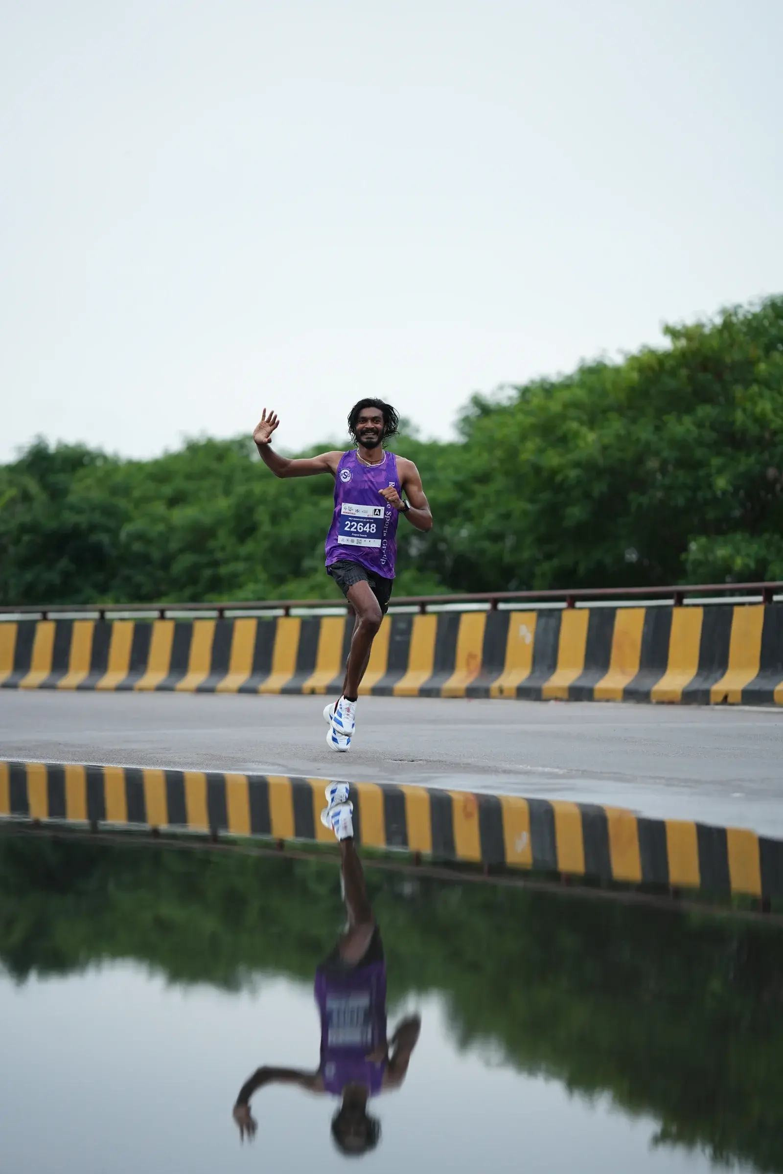 Runner in purple reflected in rainwater on the road