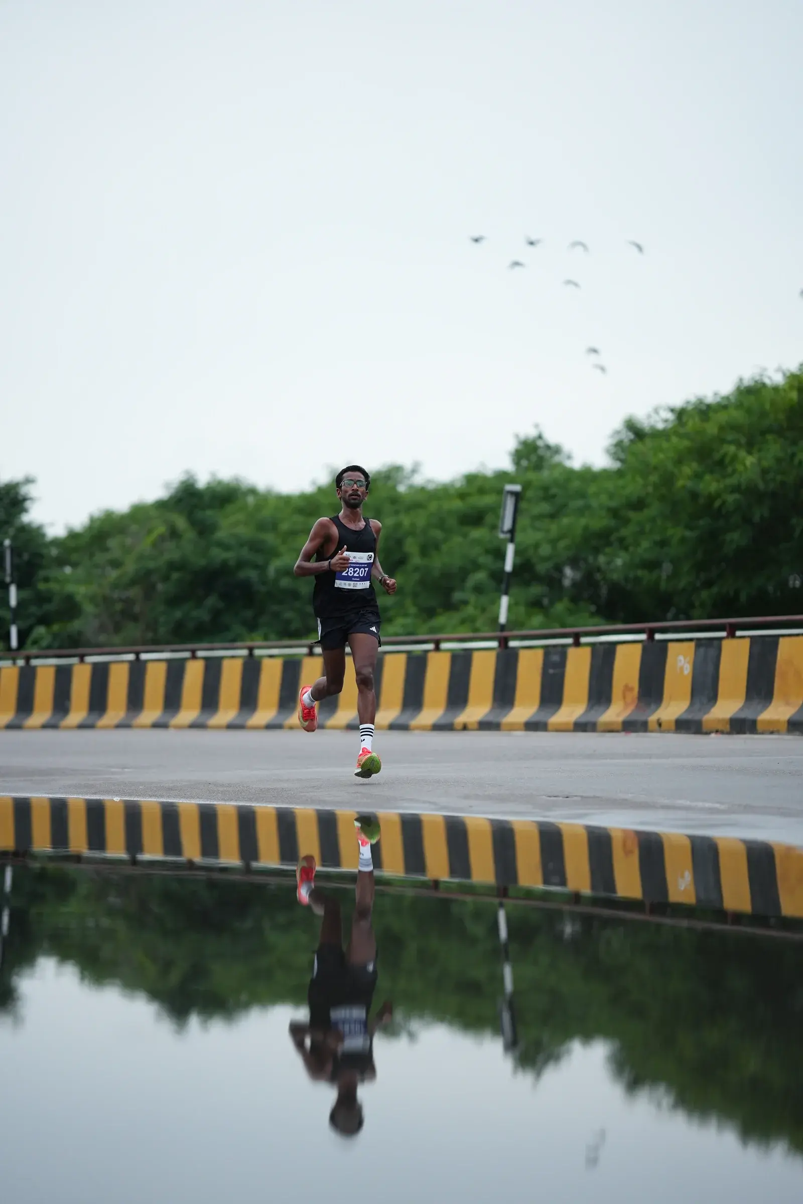 A runner passes a long puddle beneath an open sky