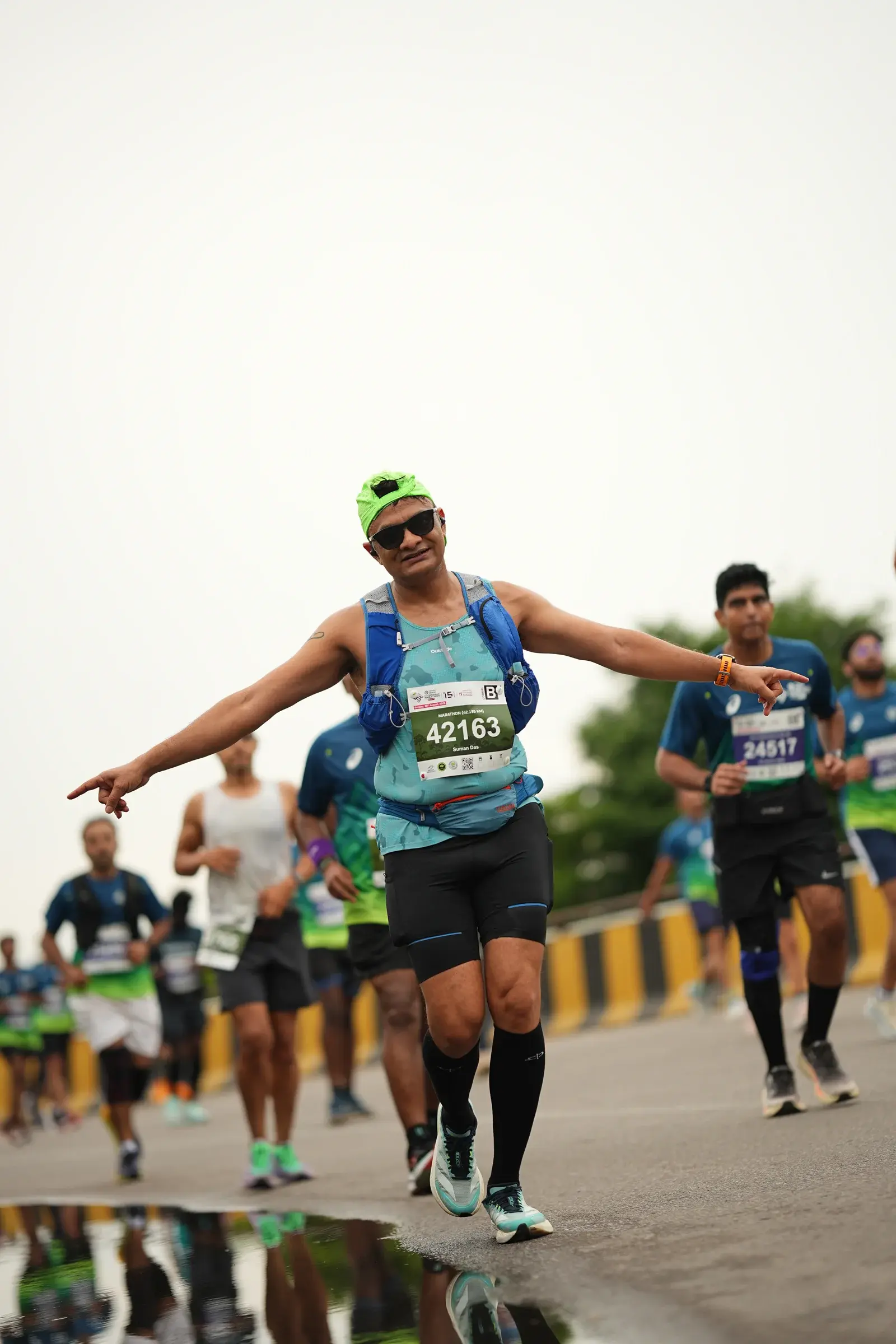 Runner in a blue vest and bright cap celebrates mid-race