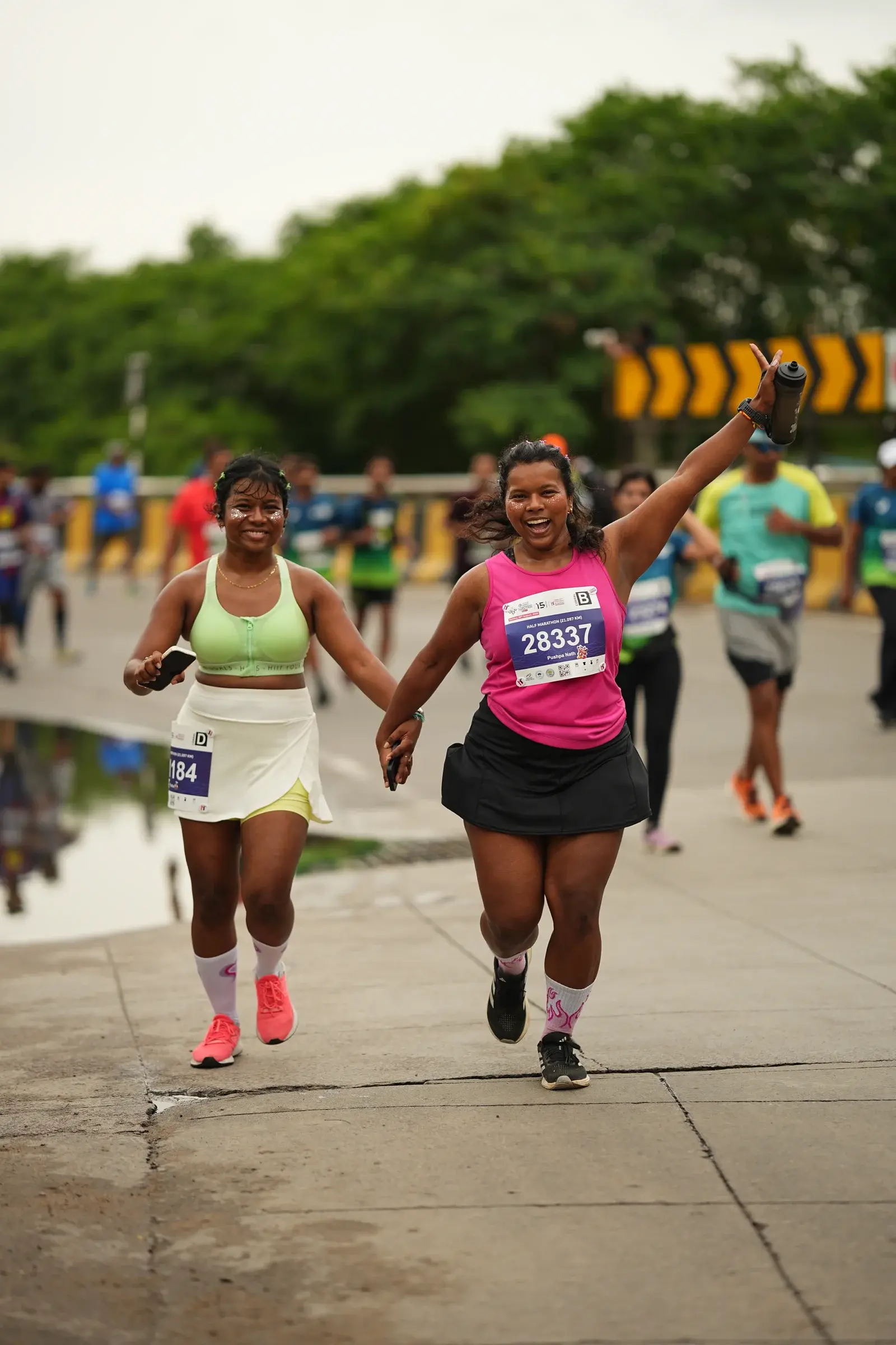 Two runners stride side by side along a tree-lined road
