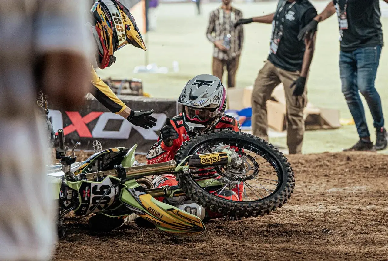 Motocross rider beside a bike in the paddock