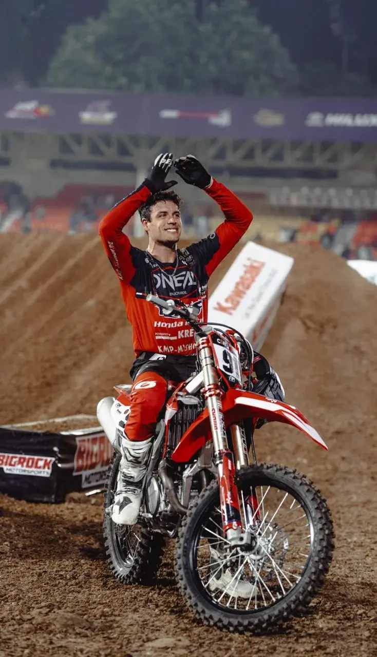 Rider celebrates from a red motocross bike